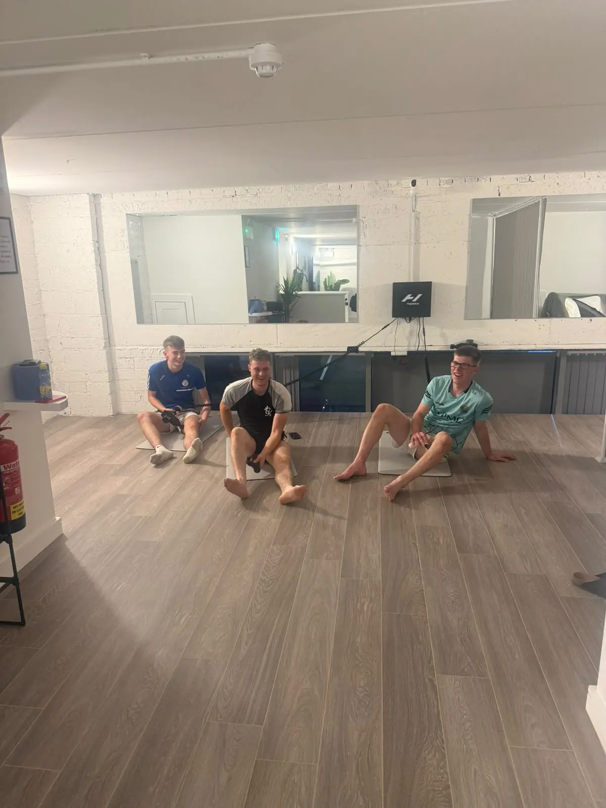 Three guests stretching on the mobility floor in front of the mirrors